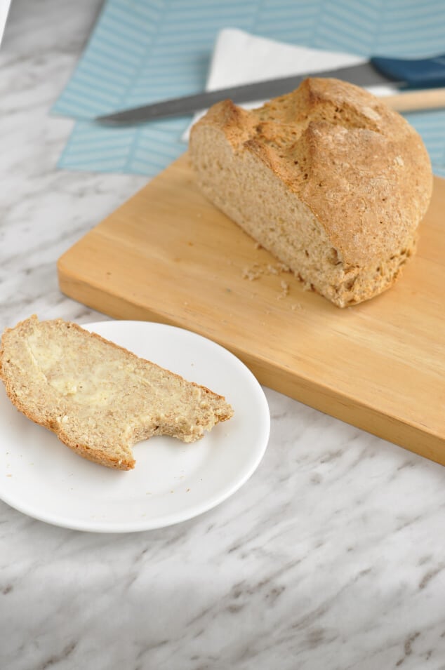 A load of easy Irish soda bread next to a plate with a slice of buttered bread.