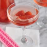 A champagne glass filled with strawberries and strawberry coconut rose sangria.