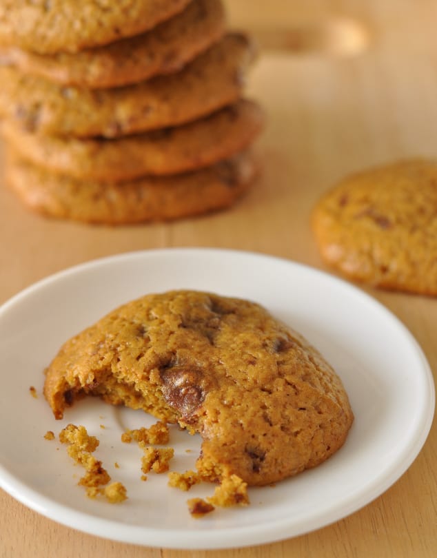 A partially eaten Healthy Pumpkin Cookie with Chocolate Chips on a white plate with crumbs