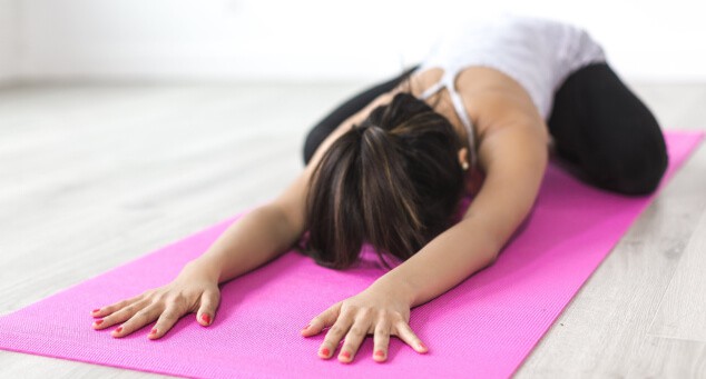 A woman practising child's post in yoga on a pink mat