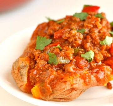 Healthy baked sweet potato with chili topping dripping over the side