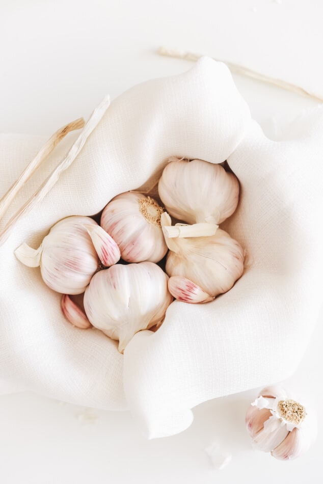 5 bulbs of garlic in a cloth-lined bowl