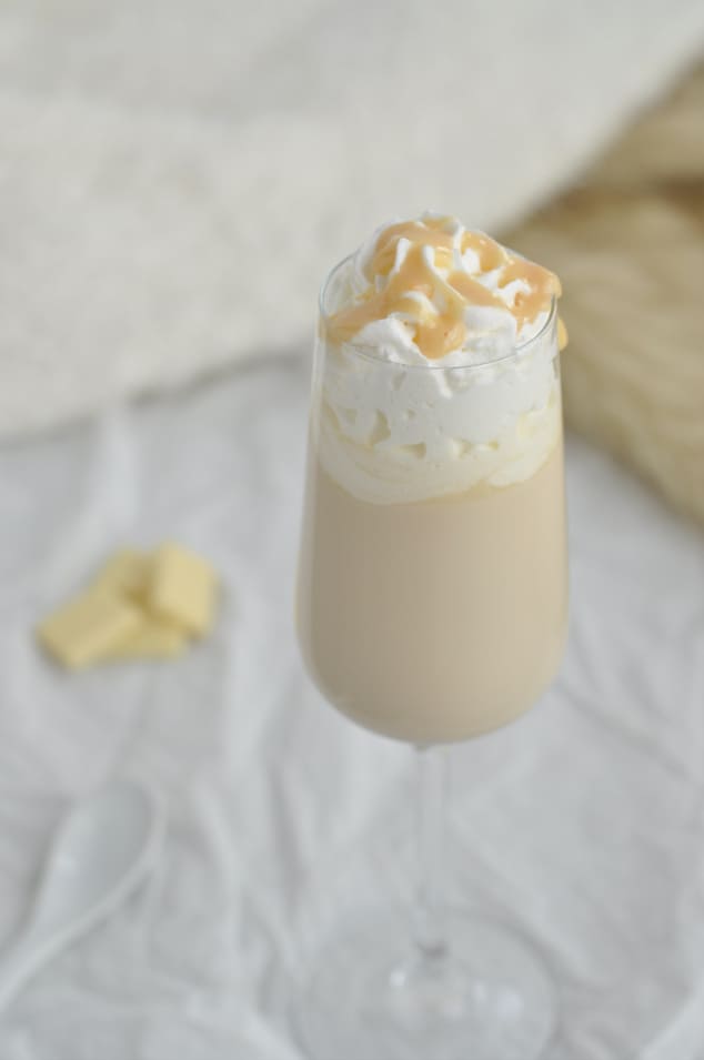 One champagne flute filled with Baileys cocktail and topped with whipped cream and caramel sauce