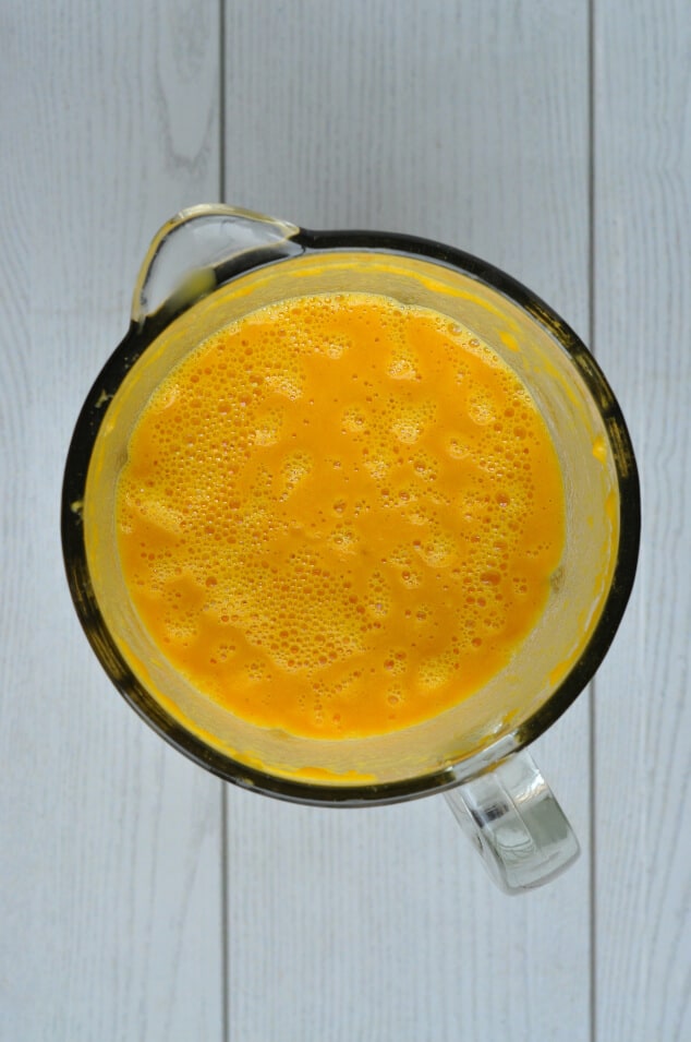 A blender filled with the blended ingredients in the creamy carrot and coriander soup recipe.