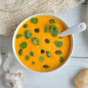 An overhead shot of creamy carrot and coriander soup in a bowl.